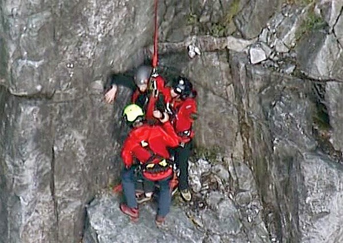  North Shore Rescue members use a helicopter longline to extract a climber from a cliff face on Crown Mountain Wednesday, after a climbing accident in which the man’s climbing partner fell to his death. photo supplied CTV Vancouver Chopper 9