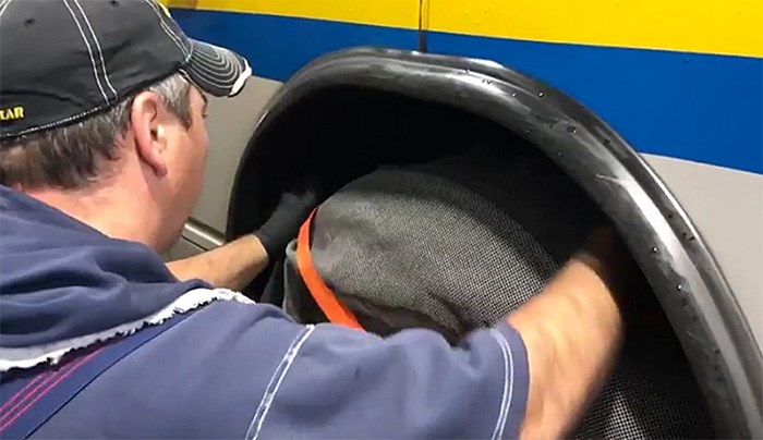  A maintenance worker demonstrates the installation of a fabric cover called a tire sock that will be piloted on buses heading up to SFU. They are used in other jurisdictions with success to prevent buses from slipping on snow and ice.