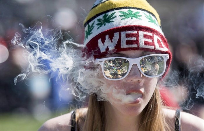  A woman exhales while smoking a joint during the annual 420 marijuana rally on Parliament hill on Wednesday, April 20, 2016 in Ottawa. The British Columbia government has set 19 as the minimum age to legally possess, purchase and consume marijuana in the province. THE CANADIAN PRESS/Justin Tang