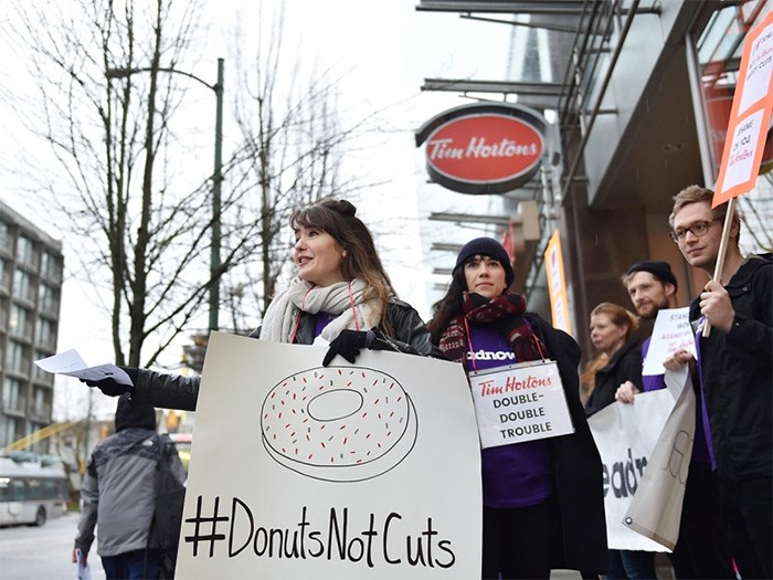  About a half dozen protesters were outside of the Broadway and Laurel location of Tim Hortons to protest cuts against some employees in Ontario. Photo Dan Toulgoet