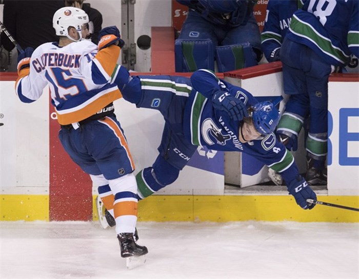  New York Islanders right wing Cal Clutterbuck (15) checks Vancouver Canucks right wing Brock Boeser (6) during third period NHL action in Vancouver, Monday, March 5, 2018. THE CANADIAN PRESS/Jonathan Hayward