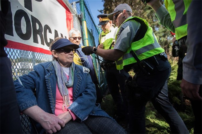 RCMP officers arrest a woman who tied herself to a gate outside Kinder Morgan in Burnaby, B.C., on Saturday March 17, 2018. Approximately 30 people who blockaded an entrance - defying a court order - were arrested while protesting the Kinder Morgan Trans Mountain pipeline expansion. The pipeline is set to increase the capacity of oil products flowing from Alberta to the B.C. coast to 890,000 barrels from 300,000 barrels. THE CANADIAN PRESS/Darryl Dyck
