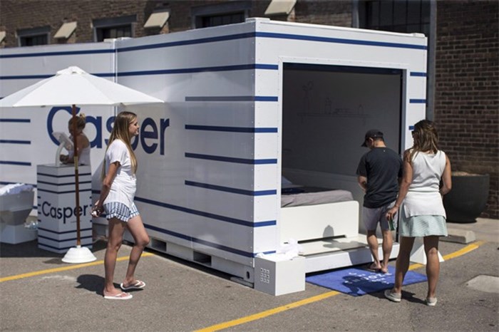  Promotional staff watch a man as he enters a pop-up installation from the mattress company Casper aimed at encouraging the public to use 