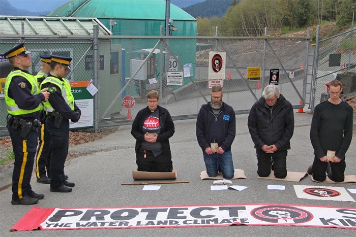  Religious leaders kneel to pray before some are arrested for violating an injunction order that prohibits blocking the entrance to the Westridge Marine terminal in Burnaby.   Photograph By Lauren Boothby