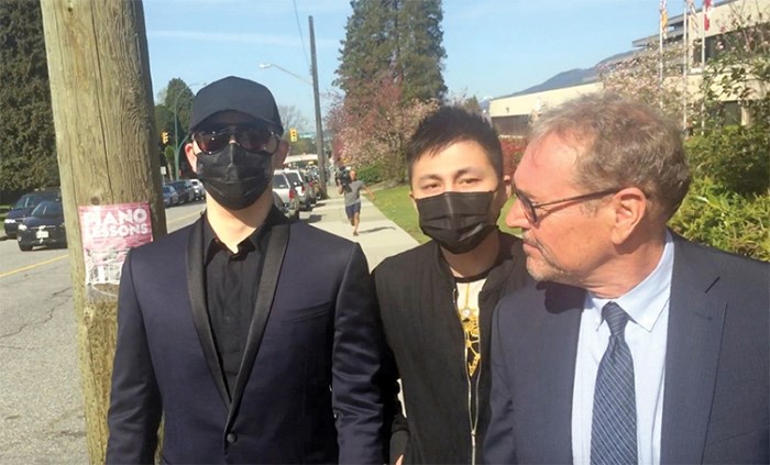  Yihao Wang, left, leaves North Vancouver provincial court in a black baseball cap, sunglasses and surgical mask, with his lawyer David Baker and an unidentified friend. photo Bob Mackin/theBreaker.news