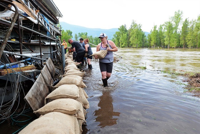  Celinda Galloway carries a sandbag along the Kettle River in Grand Forks, B.C., on Thursday, May 17, 2018. THE CANADIAN PRESS/Jonathan Hayward