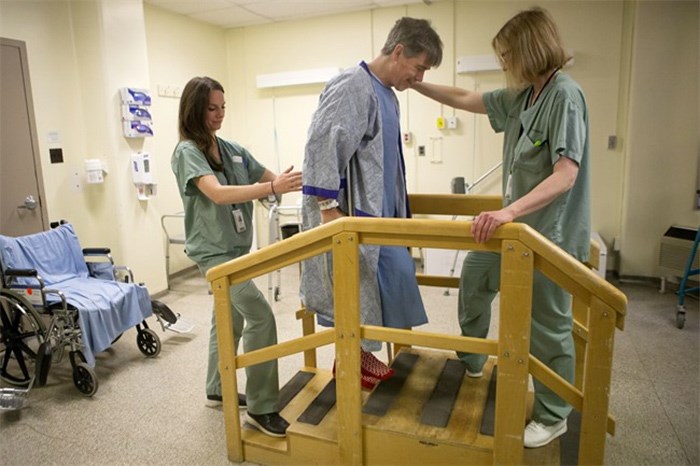  Physiotherapist Ellen Newbold, right, and occupational therapist Mary Van Impe help Tim Heenan walk up some steps as he prepares for his release following day surgery for a hip replacement at St.Michael's Hospital, in Toronto on Tuesday, May 23, 2018. THE CANADIAN PRESS/Chris Young