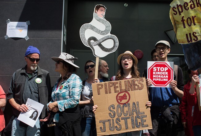  A woman holds a sign with a drawing of Prime Minister Justin Trudeau's face on a snake as protesters opposed to the Kinder Morgan Trans Mountain pipeline extension demonstrate outside Justice Minister Jody Wilson-Raybould's constituency office, in Vancouver, on Monday June 4, 2018. THE CANADIAN PRESS/Darryl Dyck