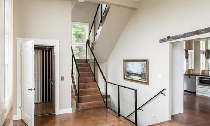  You can see the concrete floors, the elevator installed in place of a previous shaft, the stairs--including a post at the landing that is adapted from the original (Photo via RE/MAX All Points Realty)