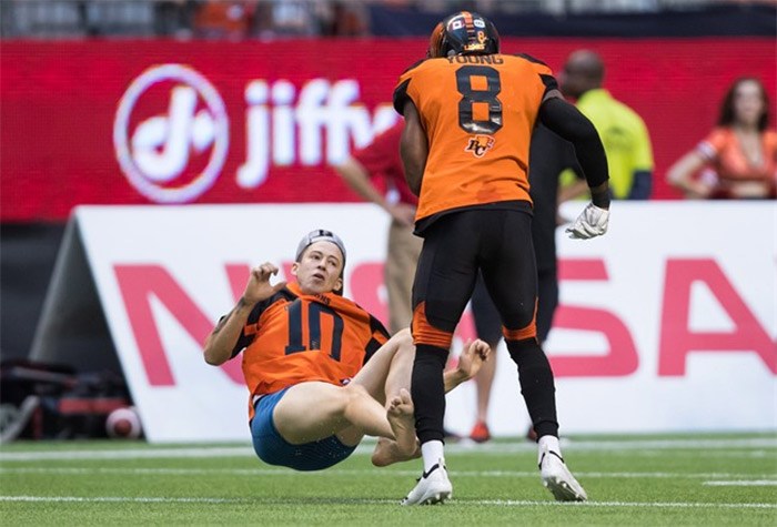  B.C. Lions' Marcell Young (8) knocks down a spectator that ran onto the field of play during the first half of a CFL football game against the Montreal Alouettes in Vancouver, on Saturday June 16, 2018. THE CANADIAN PRESS/Darryl Dyck