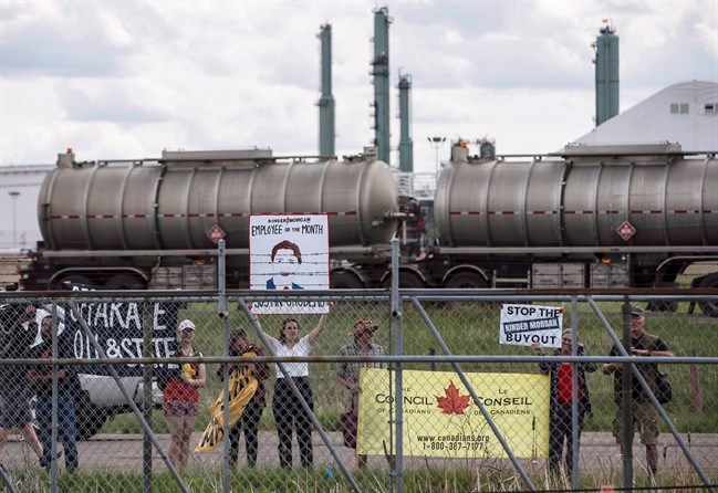  Protestors stand outside the fence as Prime Minister Justin Trudeau visits Kinder Morgan in Edmonton Alta, on Tuesday June 5, 2018. A study by a sustainable energy research group predicts the federal government's purchase of the Trans Mountain pipeline will add significantly to the deficit next year. THE CANADIAN PRESS/Jason Franson