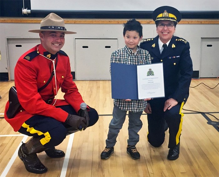 Douglas Road Elementary school student Tony Leong receives a certificate of appreciation from Burnaby RCMP Chief Supt. Deanne Burleigh, right, with school liaison officer Const. Frank Tarape. Leong pulled a kindergartener from the path of an oncoming car last month.