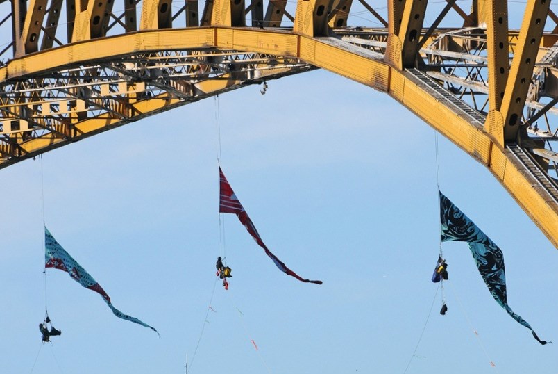  Three Greenpeace protesters hang suspended under the Ironworkers bridge Tuesday morning. The protesters aim to stop oil tankers from Burnaby's Westridge Terminal from transiting under the bridge and to denounce the federal government's decision to buy the pipeline project. File photo Cindy Goodman, North Shore News