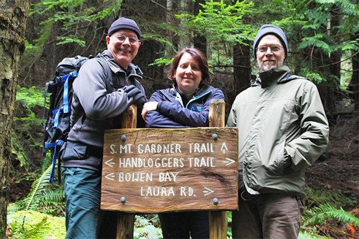  In this 2014 photo, Lynn, on the right, poses with fellow Bowen Island Rotarians Robert Ballantyne and Nancy Joyce at a Mount Gardner trailhead sign. He worked on the project to improve signage on the popular hiking trail. - Bowen Island Undercurrent