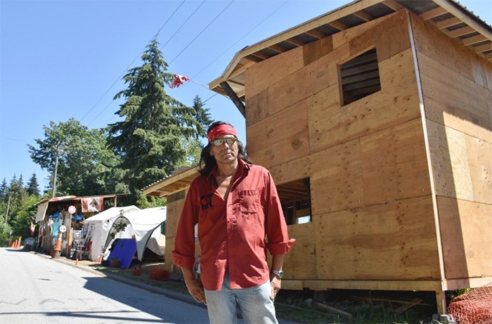  Johnny Lee stands in front of a carver's cabin he is building at Camp Cloud.