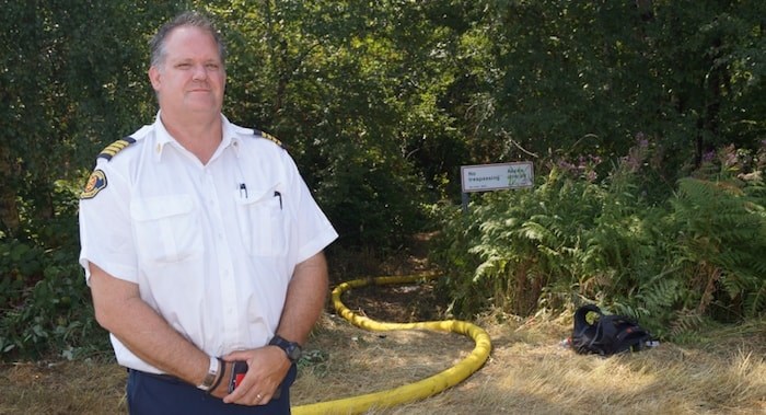  Richmond Fire Rescue Deputy Chief Kevin Gray stands at the entrance of a trail to the DND lands fire. After a week of battling the 12-hectare blaze, crews are trying to saturate the ground to extinguish an underground bog fire. (Richmond News)