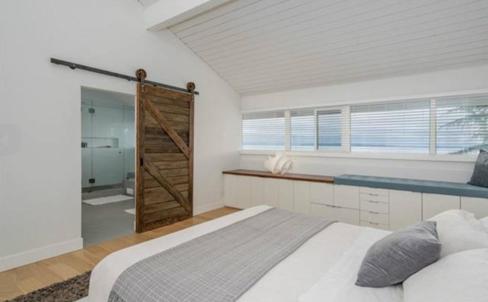  The super-cool master bedroom has horizontal strip windows looking out to the ocean, with a window seat to enjoy the views, plus a sliding barn door to the ensuite. Listing agent: Philip DuMoulin