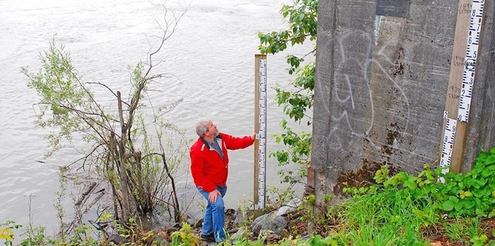  Steve Litke of the Fraser Basin Council measures Fraser River water levels at the Mission gauge. The dark plaque on the concrete marks the peak water height set in 1894. (Denise Palmer)
