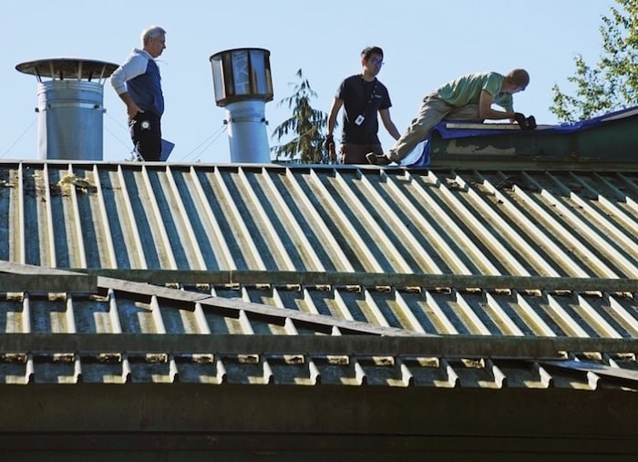  A restoration crew assesses damage atop Dorothy Lynas elementary following a rooftop fire in September 2016. The school district is suing parents of the teens who set the fire. (Photo by Cindy Goodman/North Shore News)