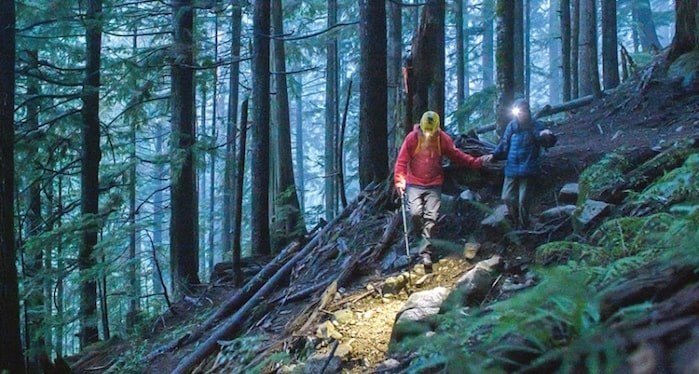  A member of North Shore Rescue helps one of the hikers down the mountain early Saturday morning. The team was called out after two women became lost near Coliseum Peak in the rain and dark on Friday night. (Photo courtesy Ian Christie)