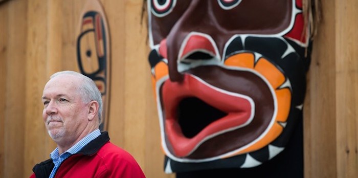  B.C. Premier John Horgan listens as a large First Nations carving of a mask is displayed during a ceremony before the raising of a replica Haida totem pole on the traditional territory of the Semiahmoo First Nation, at the Douglas-Peace Arch border crossing, in Surrey, B.C., on Friday September 21, 2018. The original pole was raised at the border crossing in the 1950s and removed without consultation or notice during the reconstruction of a visitor centre in 2008. THE CANADIAN PRESS/Darryl Dyck