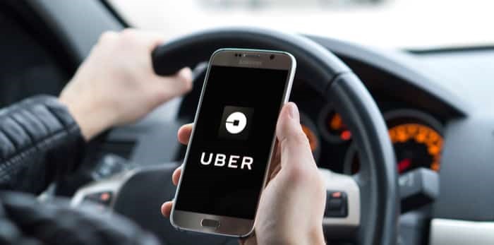  Photo: Uber driver holding smartphone in car / Shutterstock