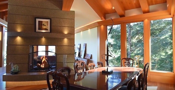  The dining area of the great room has a double-sided fireplace with an inviting den on the other side. Listing agent: Viive M. Truu. Image via YouTube