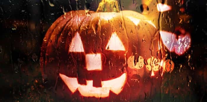  Photo: scary halloween pumpkins behind a window in the rain / Shutterstock