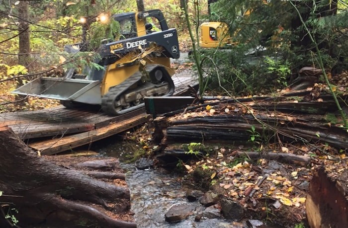  This photo shows Eagle Creek and a cracked bridge with a piece of heavy equipment crossing it.