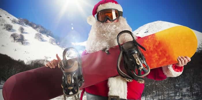  Santa Claus with snowboard in the mountains / Shutterstock