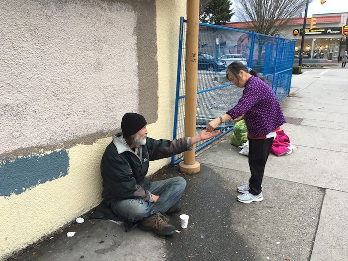  Gia Tran stops and gives some money to a person asking for change. Photo Grant Lawrence