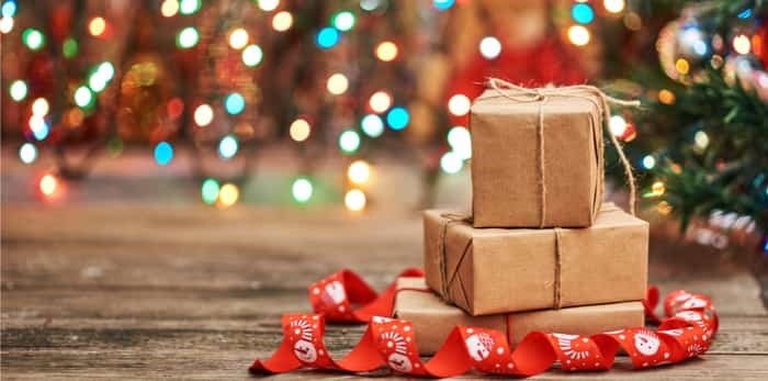  Gift boxes with a large red bow against a background bokeh of twinkling party lights. Luxury New Year gift / Shutterstock
