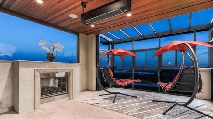  This heated indoor-outdoor sunroom has a fireplace on the left, a wall of windows to take in those amazing views in front, and a concertina door to the terrace on the right. Listing agent: Wendy Tian