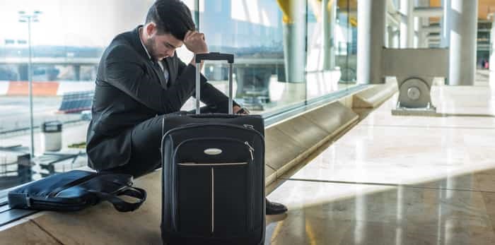  Businessman angry at the airport waiting his delayed flight with luggage / Shutterstock