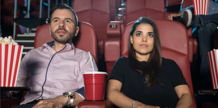  Nervous looking couple sitting next to each other at the movie theatre on their first date / Shutterstock