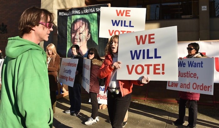  Kat Broek (orange jacket) speaks to a passerby (green) at a protest held Tuesday by the Cultural Action Party outside the Vancouver Provincial Court House where Ibrahim Ali, a Syrian refugee who is charged with the Murder of Marrisa Shen. Photo Dan Toulgoet