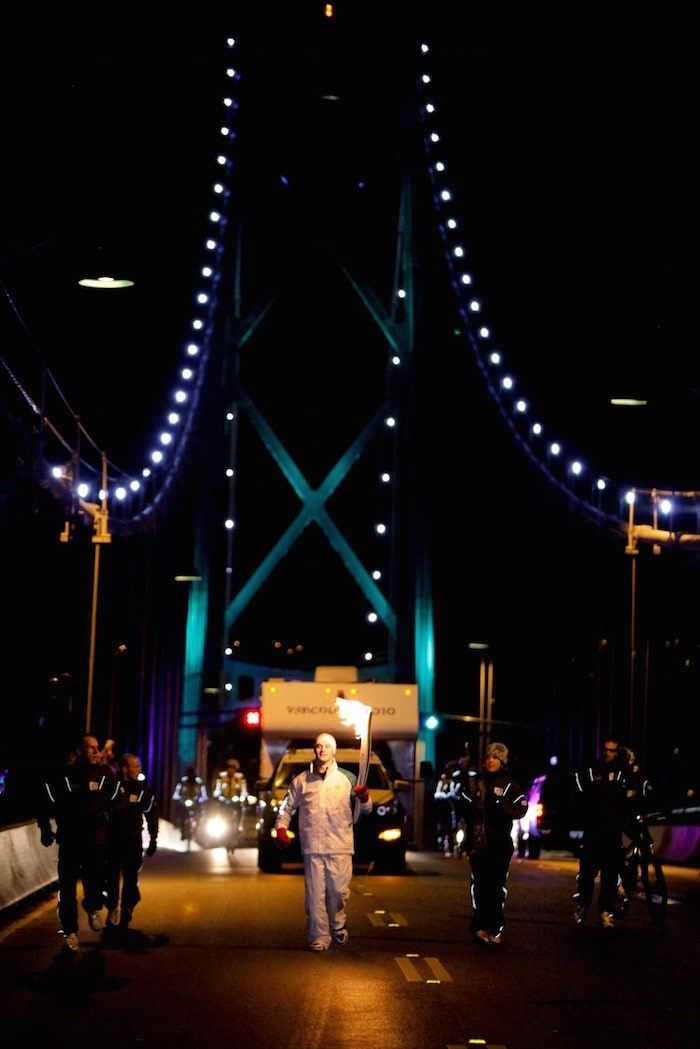  Day 106 – Torchbearer 5 Mac Stewart carries the flame across the Lions Gate Bridge in Vancouver, British Columbia. Reference code (file): AM1550-S08-3-F106 - City of Vancouver Archives / Vancouver Organizing Committee for the Olympics