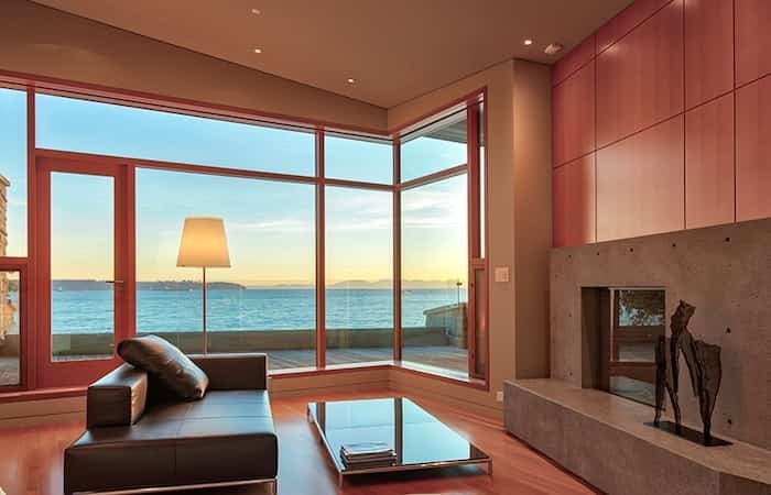  The living room has a large fireplace with a chic concrete surround topped by wood panelling, as well as massive south-west-facing windows that maximize the ocean views. Listing agent: Christa Frosch