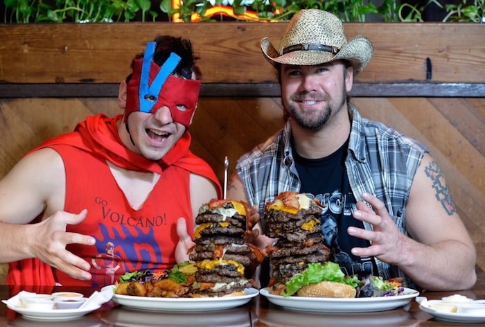   The Volcano, left, and Big Daddy Buck Lighting, who are among the wrestlers competing in the 20-person Royal City Rumble on March 30 in New Westminster, dropped by Burger Heaven on Saturday as part of a challenge to see who could eat a rumble version (10 patties) of Burger Heaven’s Ernie’s Mile High, eight-patty burger. Photo by Jennifer Gauthier