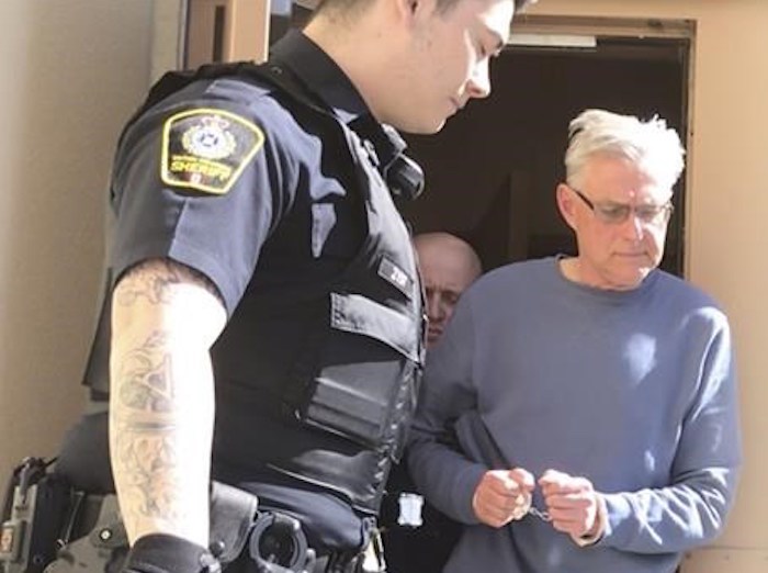  John Brittain is escorted from the RCMP detachment in Penticton, B.C., on Tuesday, April 16, 2019, in this image made from video. A Penticton, B.C., man has been charged with four counts of murder for shootings in two separate areas of the south Okanagan city on Monday. B.C. Prosecution Service spokesman Dan McLaughlin says three counts of first-degree murder and one count of second-degree murder have been laid against John Brittain. THE CANADIAN PRESS/Amy Smart