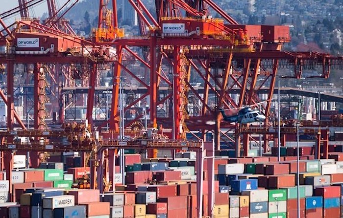  A Helijet helicopter preparing to land at the harbour passes by cranes used to load and unload container ships at the DP World marine terminal at Port Metro Vancouver, in Vancouver on March 16, 2018. Talks continued through the night between British Columbia's longshore workers union and the association representing port employers. A federal mediator imposed a news blackout as the latest round of negotiations got underway Wednesday, less than 24 hours before a lockout notice issued by the B.C. Maritime Employers Association was due to take effect. THE CANADIAN PRESS/Darryl Dyck