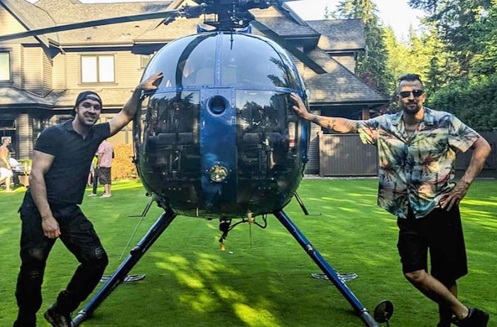  Justin Plosz, right, next to a helicopter that landed in the backyard of his Anmore home. 