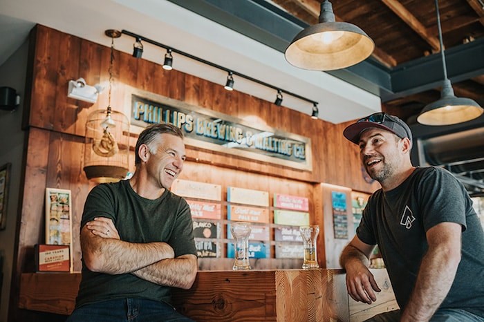  Matt Phillips of Phillips Brewing & Malting Co. (left) and Stephane Turcotte of Île Sauvage Brewing Co. (right) share a pint at the Phillips Brewing tasting room in Victoria. Photo by Meghan Goertz