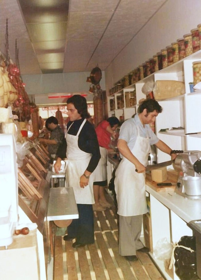  Fortunato Bruzzese cuts a wheel of cheese at the deli's original location on Commercial and First Avenue in 1977. Photo courtesy La Grotta Del Formaggio