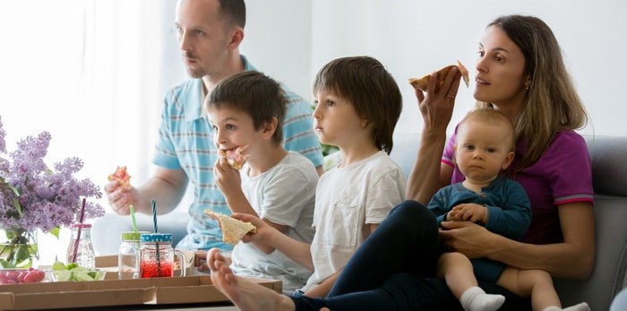  A young family eats dinner while watching television/Shutterstock