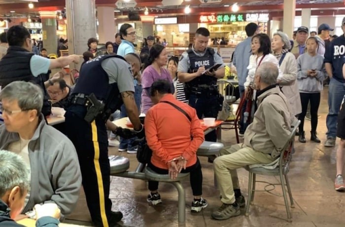  A photo posted on the Chinese social media channel WeChat shows an elderly couple being arrested at Crystal Mall after they allegedly threw soup into another woman's face Saturday. Screenshot/WeChat
