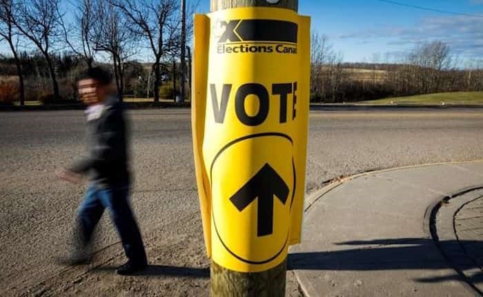  A voter walks past a sign directing voters to a polling station for the Canadian federal election in Cremona, Alta., Monday, Oct. 19, 2015. Canada's chief electoral officer says voting day this fall should not be moved. Election day can be no later than Oct. 21 under federal law, which this year falls on the Jewish holiday known as Shemini Atzeret, meaning Orthodox Jews are not permitted to work, vote or campaign. Photo: The Canadian Press / Jeff McIntosh