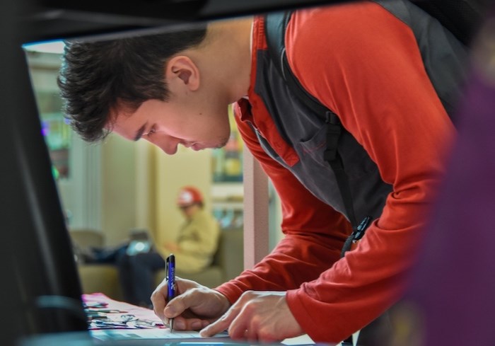  Douglas College student Jonah Roesler, 22, signs a pledge to vote in the upcoming federal election. Photo by Stefan Labbé/Tri-City News