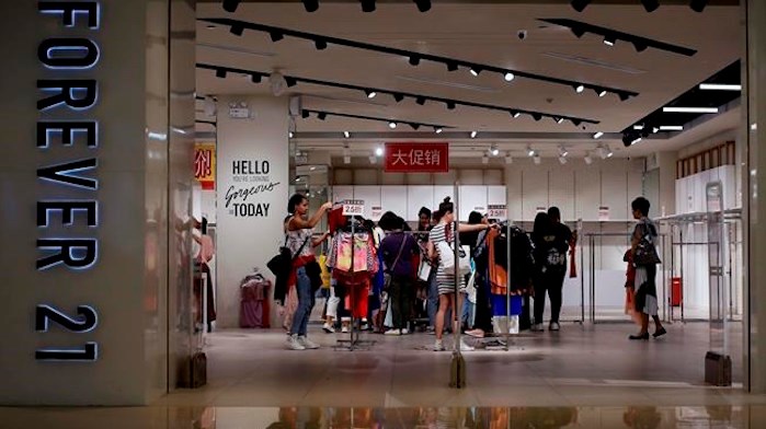  FILE - In this Tuesday, May 7, 2019, file photo, women select clothing at an American fast fashion retailer Forever 21 which is offering clearance discounts at a shopping mall after it pulled out from China's market, in Beijing. Low-price fashion chain Forever 21, a one-time hot destination for teen shoppers that fell victim of its own rapid expansion and changing consumer tastes, announced Sunday, Sept. 29, 2019, that it has filed for Chapter 11 bankruptcy protection. AP Photo/Andy Wong, File