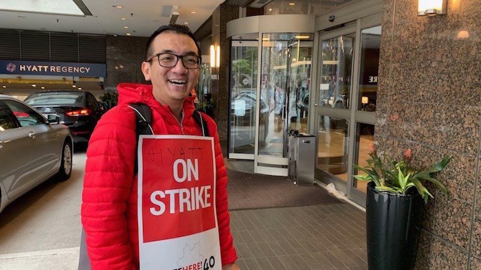  Hyatt Regency doorman Henry Tun stands outside his hotel with a picket sign. Photo by Glen Korstrom/Business In Vancouver